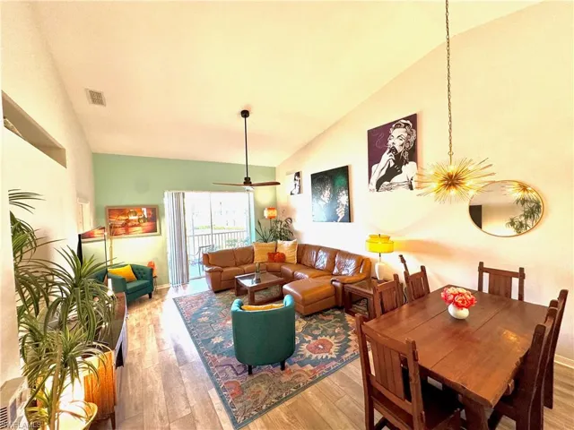 Dining space with ceiling fan with notable chandelier, high vaulted ceiling, and light wood-type flooring