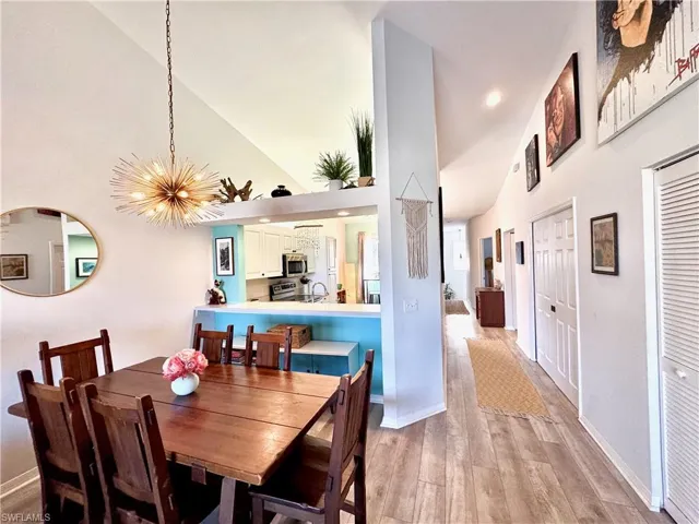 Dining space featuring lofted ceiling, sink, a notable chandelier, and light hardwood / wood-style floors