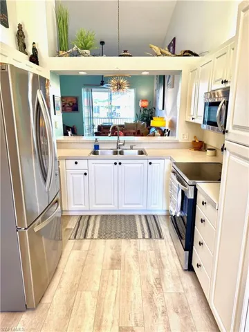 Kitchen with sink, vaulted ceiling, kitchen peninsula, stainless steel appliances, and white cabinets