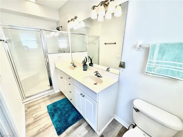 Bathroom featuring vanity, toilet, an enclosed shower, and hardwood / wood-style floors