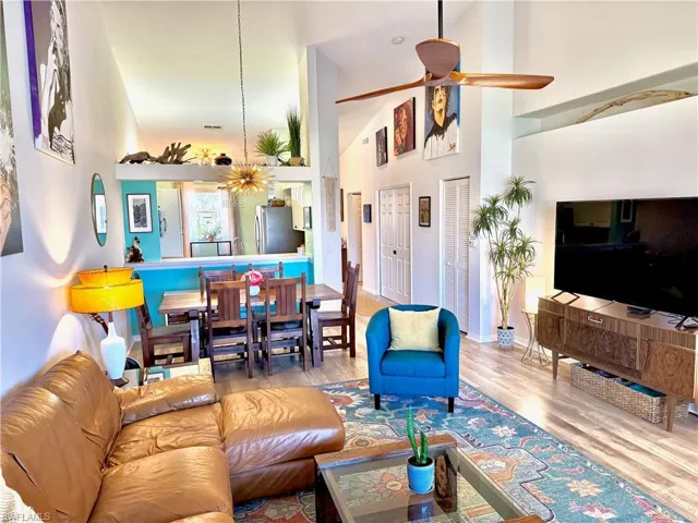 Living room featuring ceiling fan, light hardwood / wood-style flooring, and a high ceiling