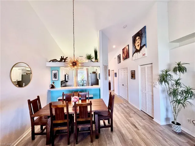 Dining area with high vaulted ceiling and hardwood / wood-style floors