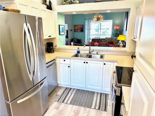 Kitchen with white cabinetry, stainless steel appliances, sink, and light hardwood / wood-style flooring