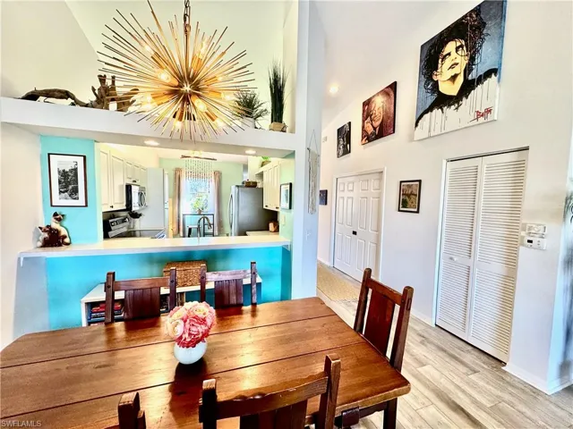 Dining area with a high ceiling, sink, an inviting chandelier, and light hardwood / wood-style flooring