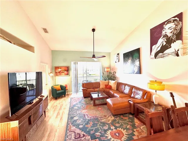 Living room featuring ceiling fan, vaulted ceiling, and light wood-type flooring