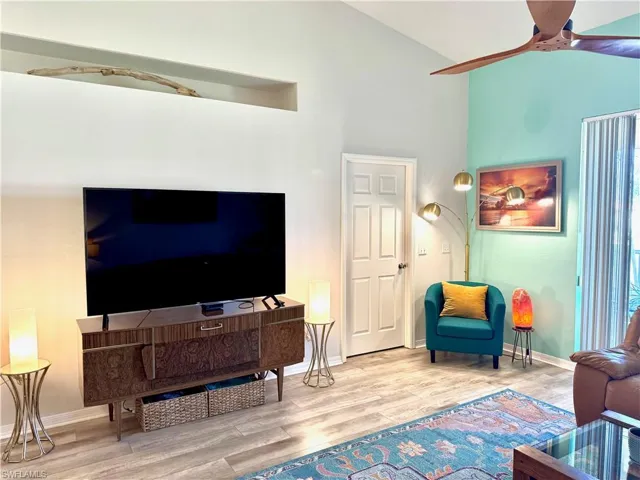 Living room with ceiling fan, lofted ceiling, and wood-type flooring