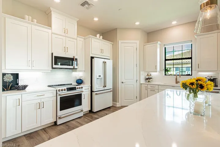 Kitchen with white cabinets, white appliances, backsplash, light stone countertops, and recessed lighting