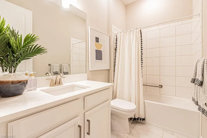 Bathroom featuring shower / tub combo, vanity, and light tile patterned flooring
