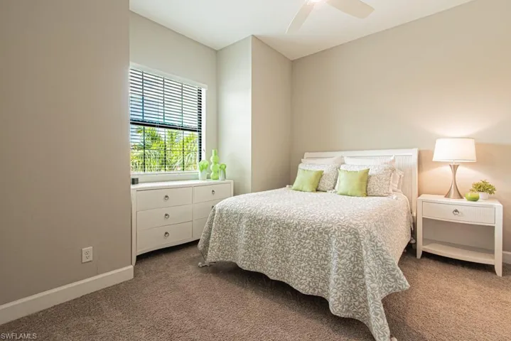 Carpeted bedroom with a ceiling fan and baseboards