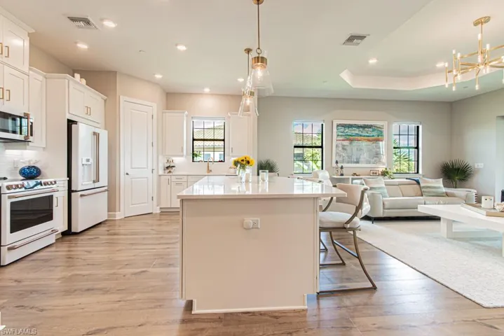 Kitchen featuring white appliances, open floor plan, light wood finished floors, plenty of natural light, and recessed lighting