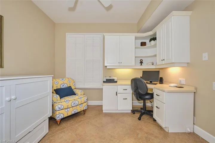 Home office featuring built in desk, light tile patterned floors, and ceiling fan