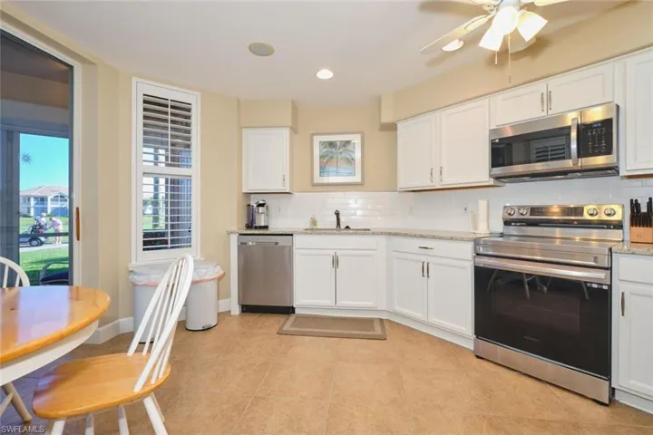 Kitchen featuring appliances with stainless steel finishes, backsplash, white cabinetry, light stone counters, and recessed lighting