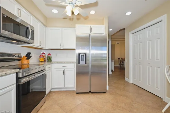 Kitchen with stainless steel appliances, recessed lighting, white cabinetry, light stone countertops, and tasteful backsplash