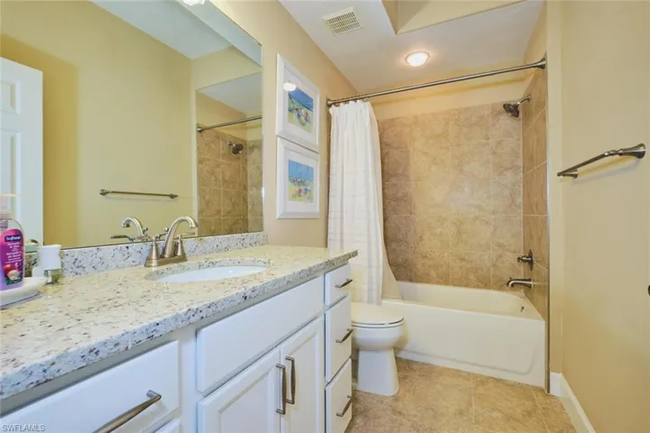 Bathroom with vanity, shower / bath combination with curtain, and light tile patterned floors