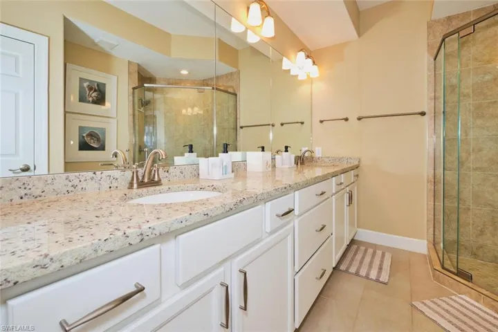 Full bath featuring a stall shower, double vanity, and light tile patterned floors