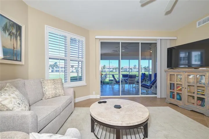 Living room featuring a ceiling fan, light tile patterned floors, and a sunroom