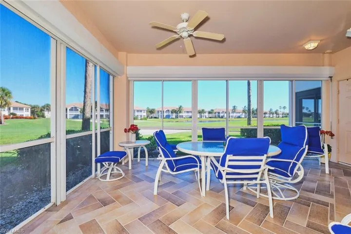 Sunroom with view of golf course and a residential view