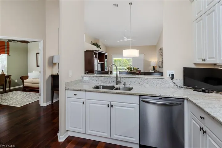 Kitchen featuring a stainless steel undermount sink, granite countertops, white cabinetry, and a stainless steel dishwasher