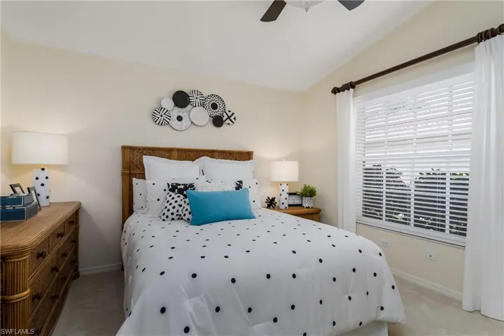 Bedroom featuring a rattan headboard, carpet flooring, and a window with horizontal blinds and draperies
