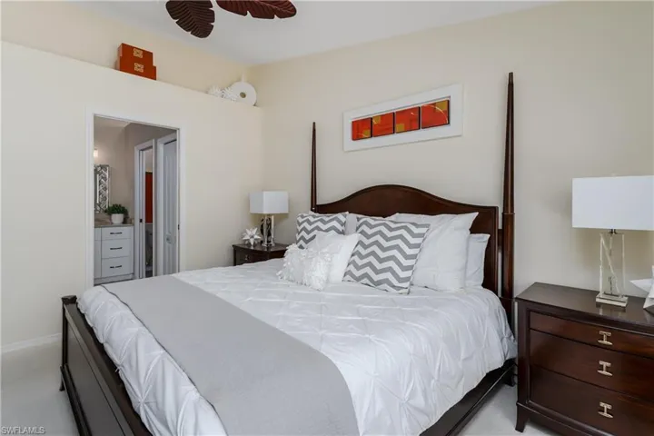 Bedroom featuring light-toned walls, a dark wood-finish four-poster bed frame, and carpeted flooring