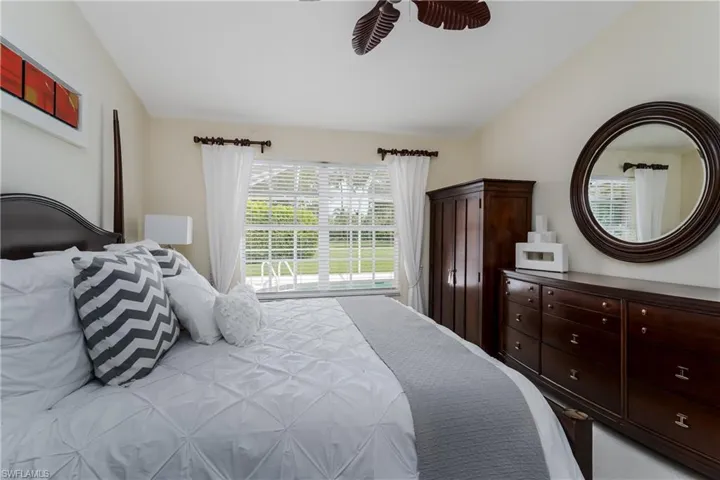 Vaulted ceiling with a tropical-style ceiling fan, large window with horizontal blinds, and direct outdoor access