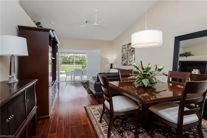 Open-concept living area featuring wood-finish flooring, a vaulted ceiling, and a contemporary drum pendant light