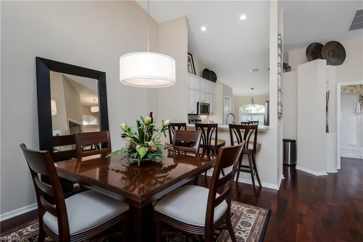 Dining area featuring wood-finish flooring, a contemporary drum pendant light, and a large wall mirror
