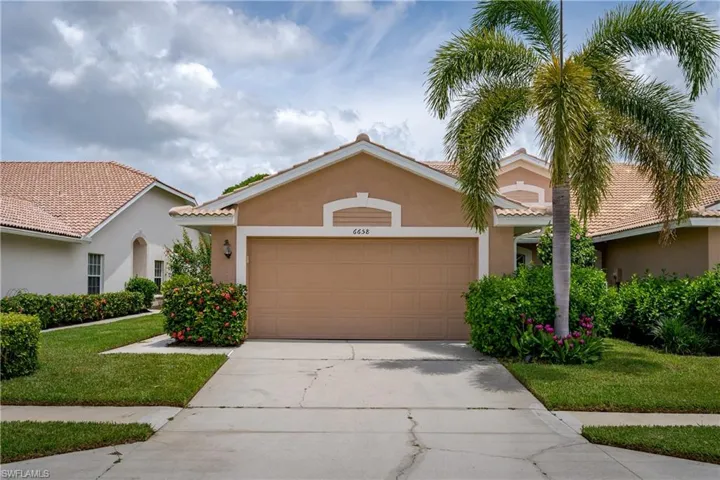 Stucco exterior with a tiled roof, featuring an attached garage and a concrete driveway