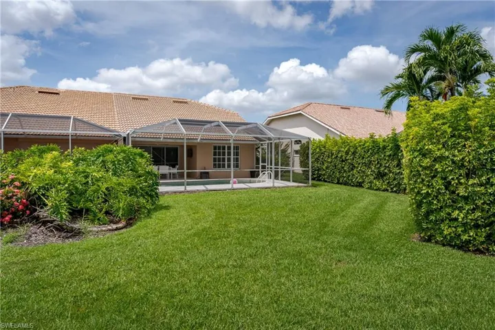 Expansive backyard with manicured lawn and mature privacy hedges