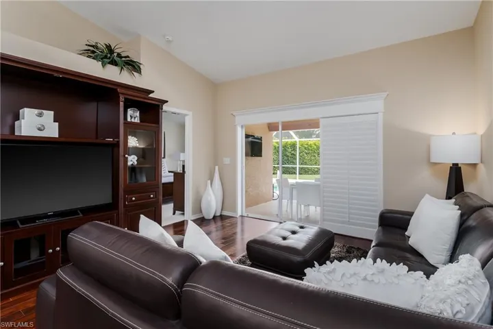 Living area featuring wood-finish flooring, a built-in media cabinet, and a vaulted ceiling