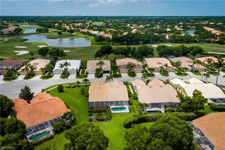Aerial perspective showcasing a residential community with numerous homes featuring screened pools