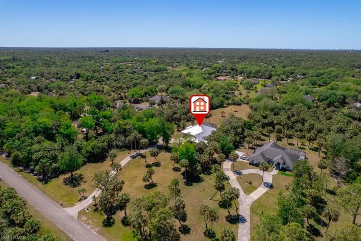 Front Birds eye view of property with a view of trees