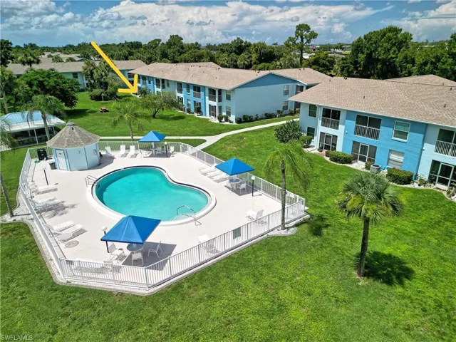 Heart-shaped swimming pool with a surrounding paved deck, white perimeter fencing, and two blue shade canopies