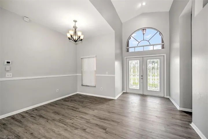 Entryway featuring lux vinyl flooring, a notable chandelier, french doors, and high vaulted ceiling