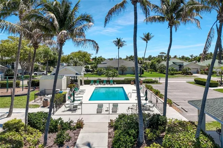 Heated swimming pool featuring a surrounding concrete deck, perimeter fencing, and cabana.