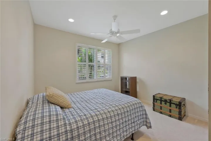 Guest bedroom with plantation shutters, ceiling fan, recessed lighting, and neutral carpet.