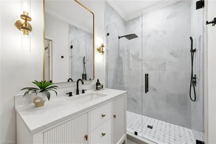 Primary bathroom fully gutted and renovated in Feb 2026. Walk-in shower with glass panel door, multiple shower heads, stone top vanity with storage and dimmable wall sconces.