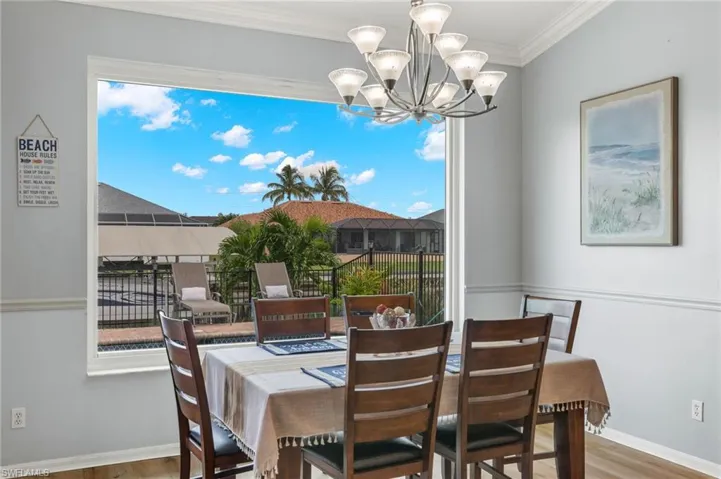 Dining space featuring a notable chandelier, a wealth of natural light, ornamental molding, and hardwood / wood-style flooring