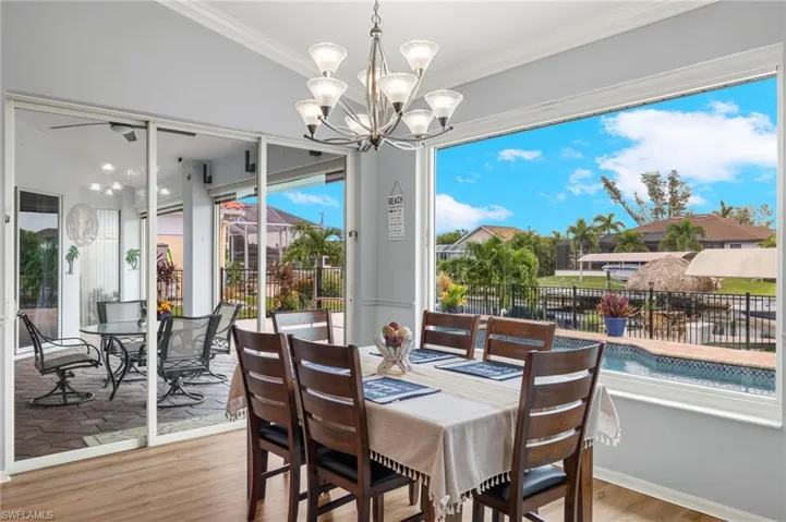 Dining area featuring light wood-type flooring, ornamental molding, a chandelier, and vaulted ceiling