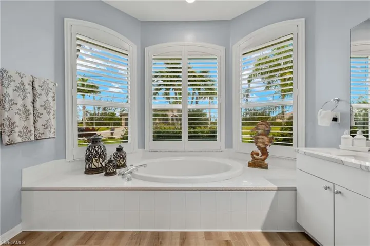 Bathroom featuring hardwood / wood-style floors, tiled bath, and vanity