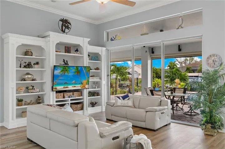 Living room with ceiling fan, light wood-type flooring, and crown molding