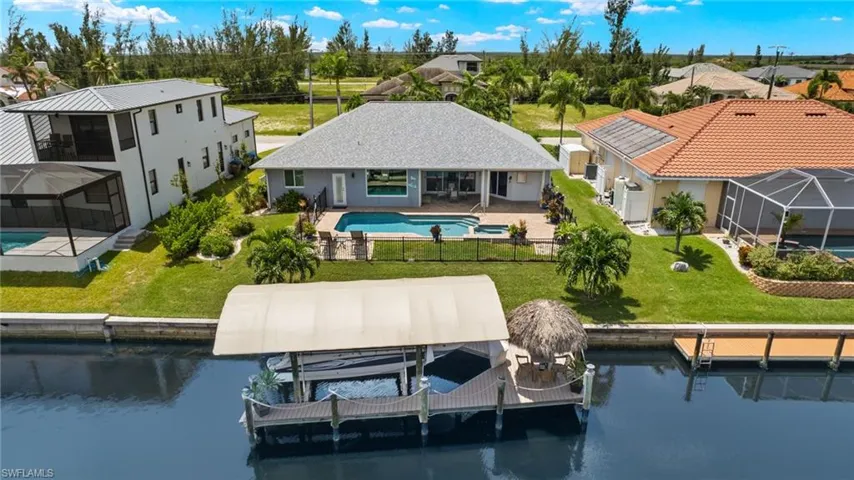 Back of property with a lanai, a patio, a water view, and a yard