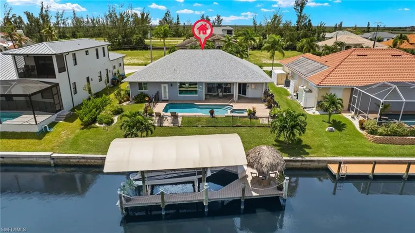 Back of house with a lanai, a patio, a water view, and a yard