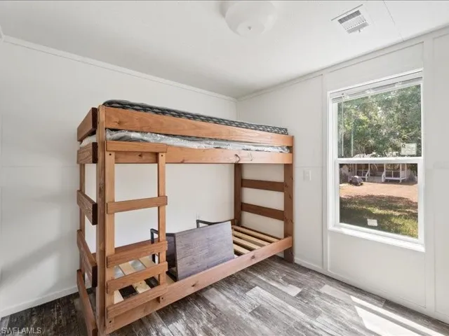 Unfurnished bedroom with visible vents and wood finished floors