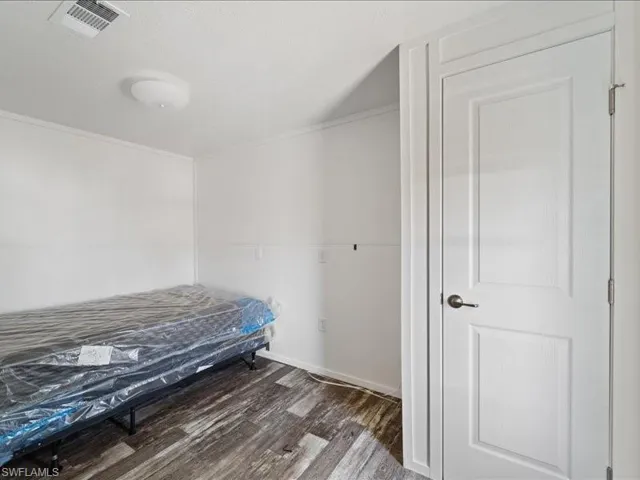 Bedroom featuring ornamental molding, visible vents, and wood finished floors