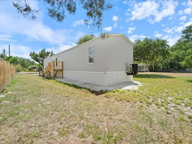 View of property exterior featuring central AC, fence, and a yard