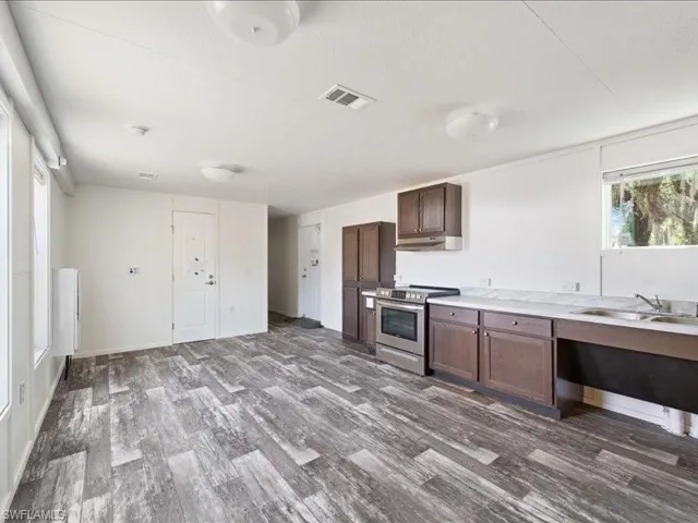 Kitchen with dark wood-style floors, a sink, under cabinet range hood, and stainless steel range with electric cooktop