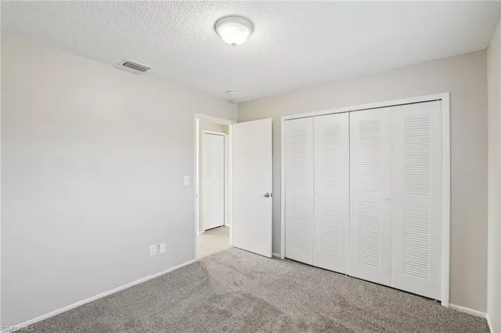Unfurnished bedroom with a textured ceiling, carpet floors, and a closet