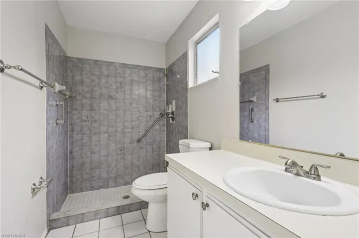 Full bath with a tile shower, vanity, and light tile patterned floors