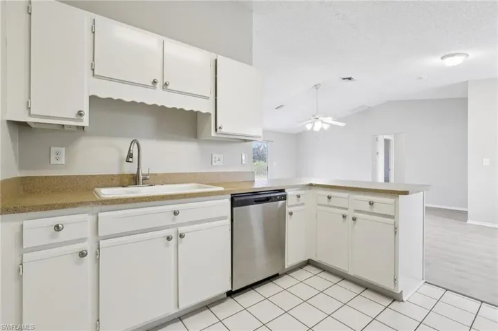 Kitchen with a peninsula, white cabinetry, dishwasher, light countertops, and a textured ceiling